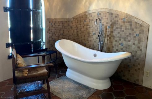Bathroom with light colored walls, tiled flooring, and white cast iron slipper tub