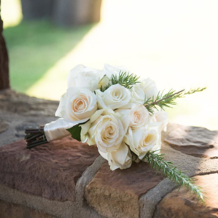 Close up view of a bouquet made with white and pink roses and evergreen sprigs