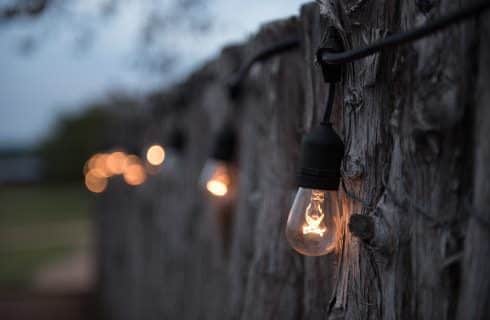 Close up view of a string of outdoor Edison light bulbs hanging on a wooden fence