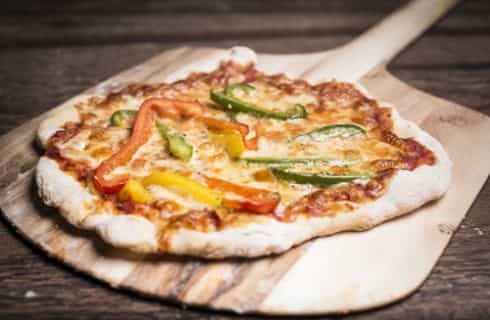 Close up view of wood fired pizza on wooden pizza paddle